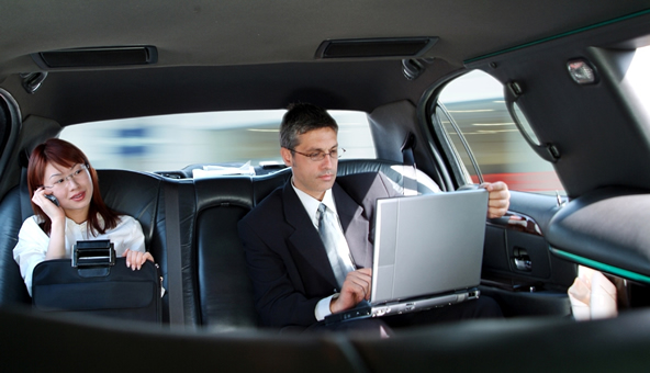 A man with a laptop and a woman taking a ride with limo service Downey